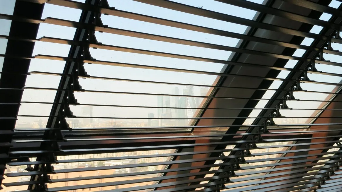 Vue à travers des stores modernes, avec des bâtiments flous en arrière-plan, offrant une perspective architecturale unique.