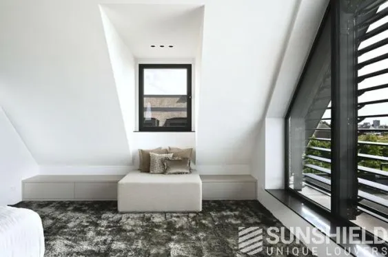 Intérieur moderne d’une chambre sous les combles, avec un grand tapis et un coin détente confortable près d’une fenêtre.