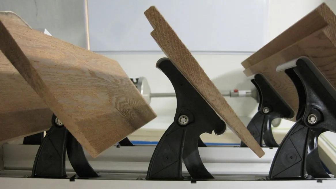 Éléments en bois maintenus par des serre-joints, montrant une préparation pour le travail du bois en atelier.