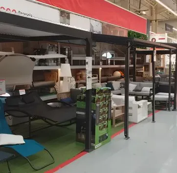 Mobilier d’extérieur présenté en rayonnage avec canapés, chaises longues et accessoires de jardin dans un magasin.