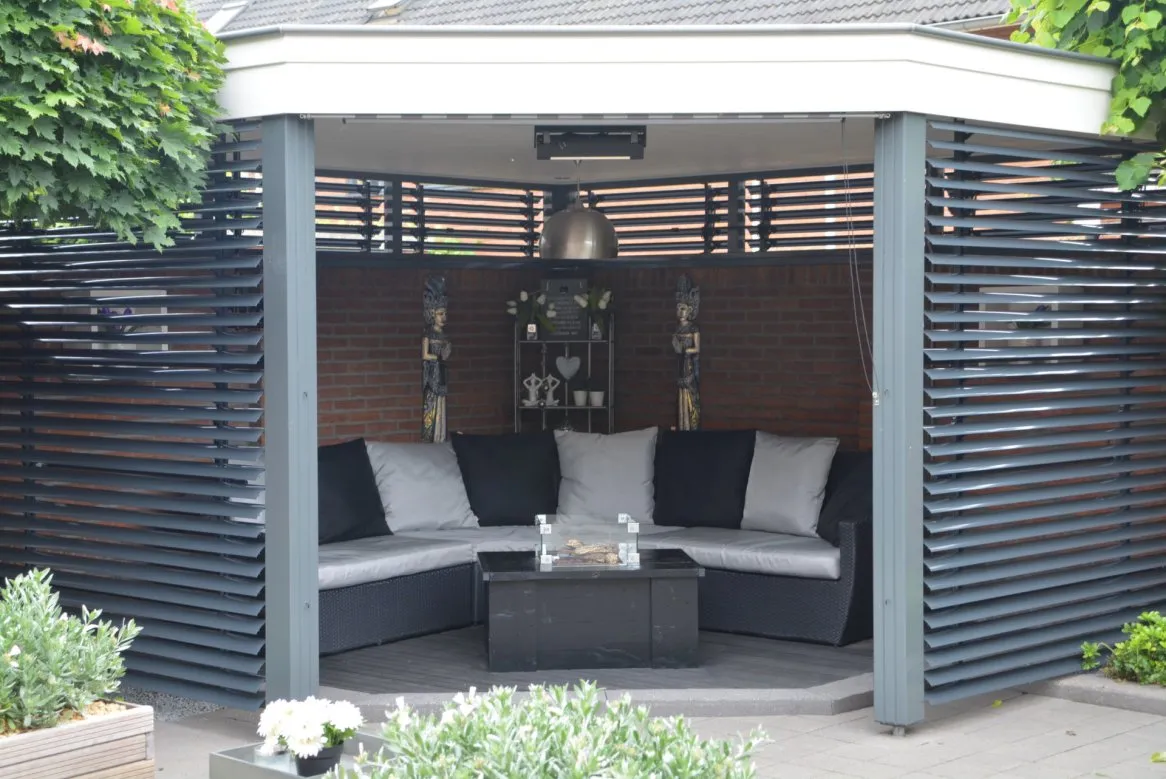 Espace lounge extérieur moderne avec canapé gris et noir, table basse, lumineux et entouré de lattes en bois.