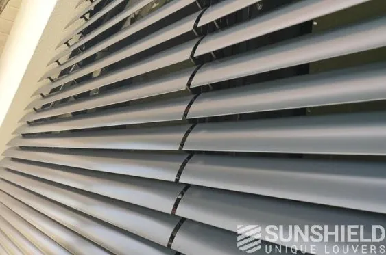 Persiennes en métal gris, vues de près, offrant une protection contre le soleil et une touche moderne à l’intérieur.