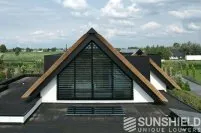 Maison moderne avec toit à pignons, fenêtres en volets, et harmonie entre architecture contemporaine et nature environnante.