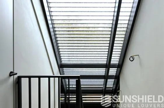 Escalier moderne avec un plafond vitré et une rambarde en métal, apportant luminosité et esthétique à l’espace.