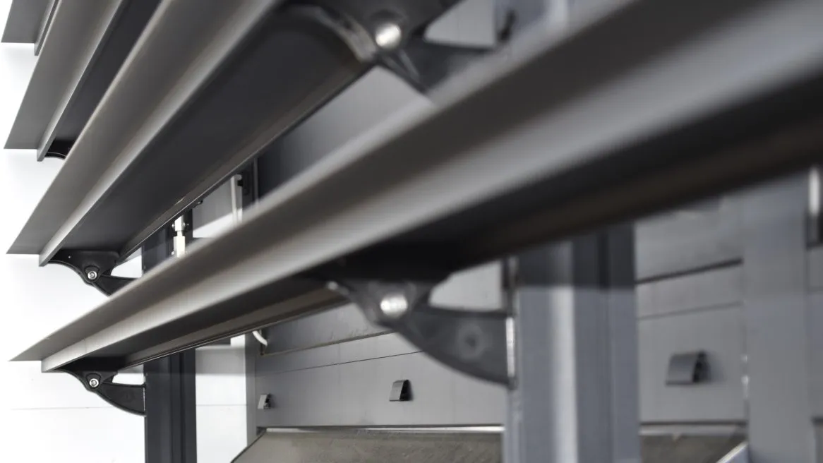 L’image montre des lames de store en métal, alignées avec des supports, dans un cadre moderne et minimaliste.