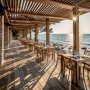 Terrasse d'un restaurant en bord de mer, tables en bois, lumière du (…)