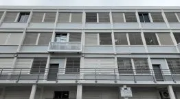 Façade d’un bâtiment moderne avec volets horizontaux, balcons et fenêtre, dans un style architectural contemporain.