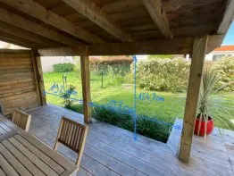 Terrasse en bois avec dimensions indiquées, espace vert visible à l’extérieur. Idéal pour créer un coin détente.