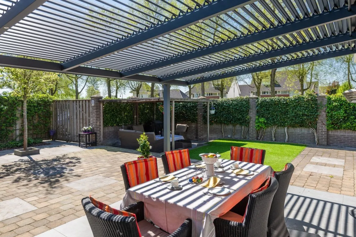 Table à manger élégante sous une pergola, entourée d’un jardin verdoyant, idéale pour les repas en plein air.