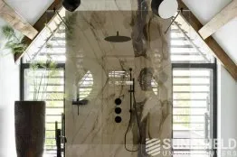 Salle de bain moderne avec douche en marbre, plantes vertes et éclairage minimaliste, ambiance élégante et apaisante.