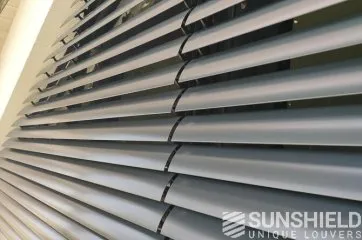 Persiennes en métal gris, vues de près, offrant une protection contre le soleil et une touche moderne à l’intérieur.