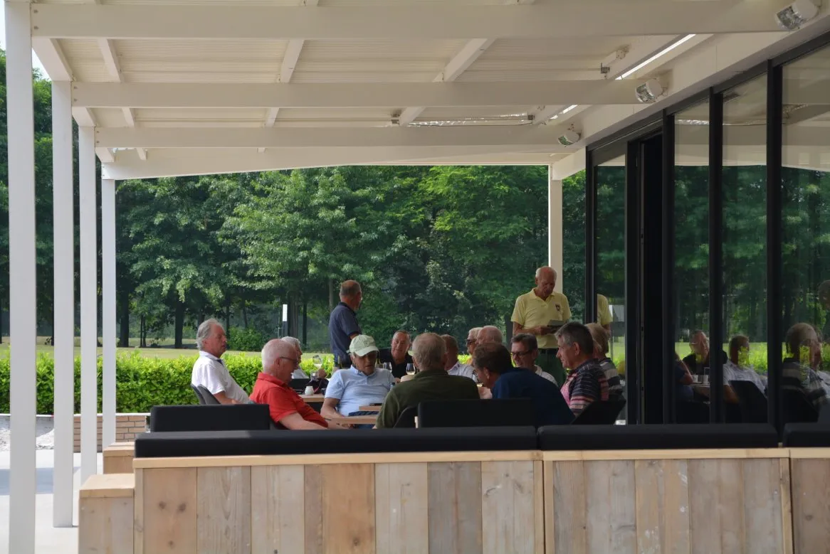 Un groupe de personnes âgées discute sur une terrasse, entouré de verdure et d’un espace moderne et convivial.
