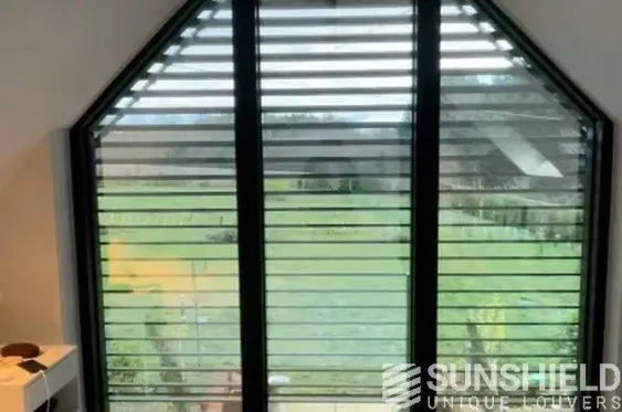 Fenêtre avec des volets métalliques, vue sur un jardin verdoyant, ambiance moderne et lumineuse.