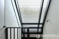 Escalier moderne avec un plafond vitré et une rambarde en métal, apportant luminosité et esthétique à l’espace.